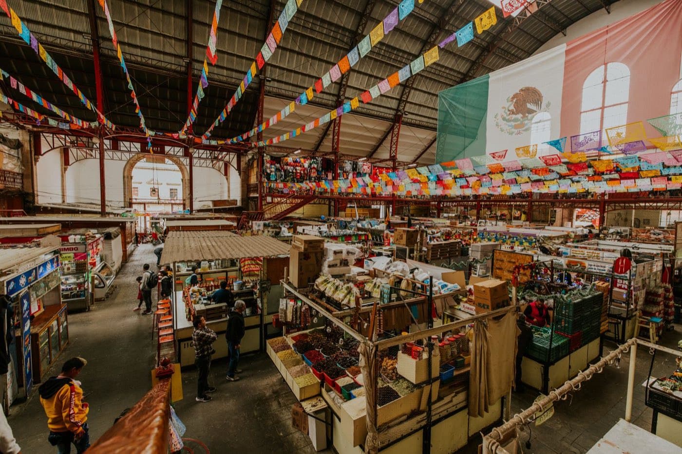 Mercado latino con puestos de abarrotes y papel picado de colores