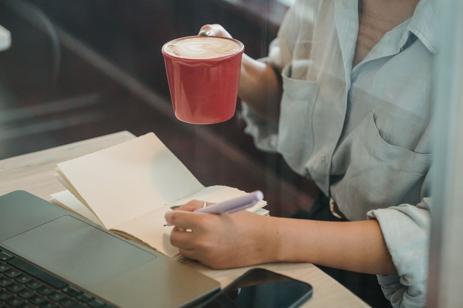 Persona escribiendo en una libreta en un café