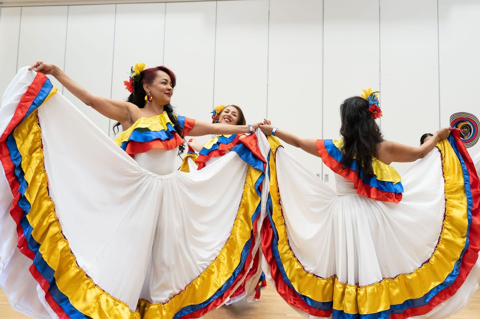 Bailarinas con trajes típicos colombianos, de falda blanca y volantes con los colores de la bandera, en «Arte que Abraza»