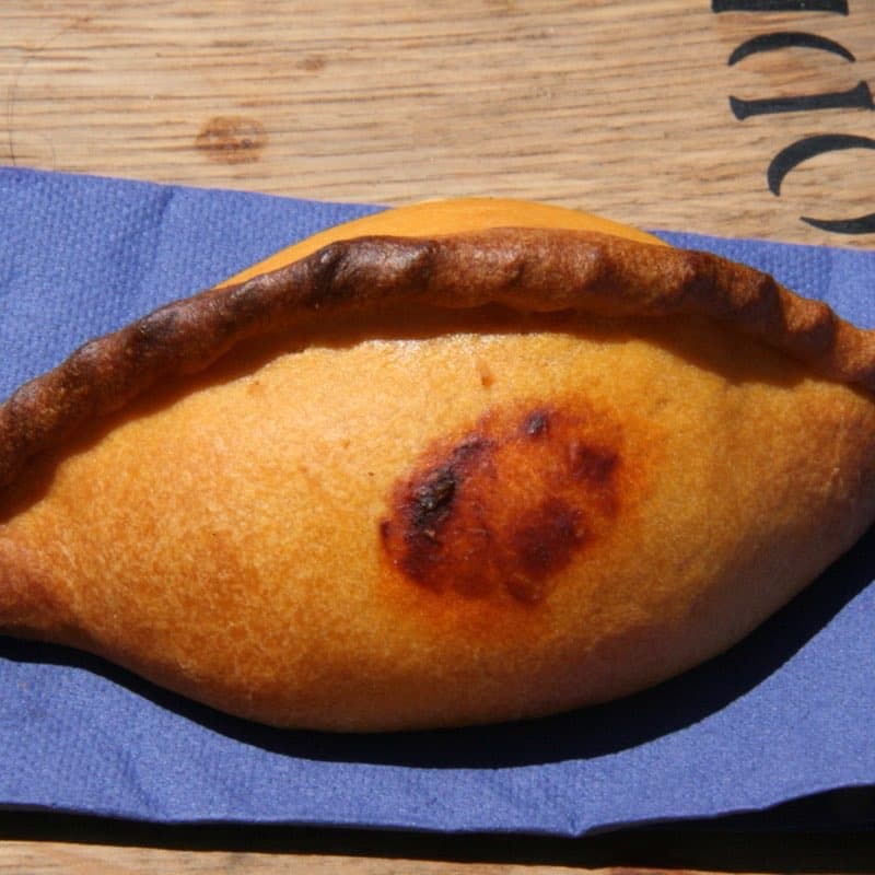 Salteña boliviana recién horneada, dorada y con su repulgue